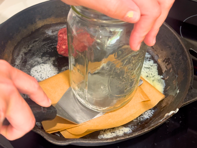 smashing burgers with a mason jar and spatula